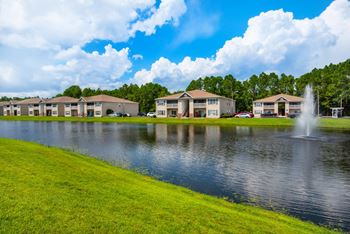 A row of apartment buildings with a fountain in the pond in front at Crystal Lake in Pensacola, Florida.